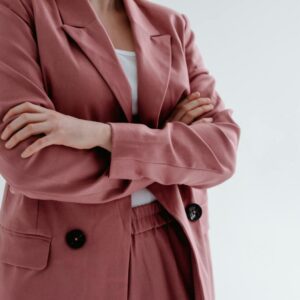 Close-up of a woman in a pink blazer with arms crossed, conveying confidence.