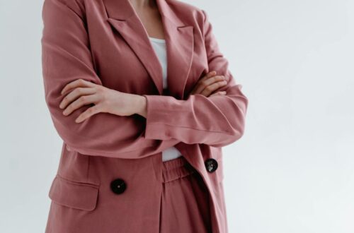 Close-up of a woman in a pink blazer with arms crossed, conveying confidence.